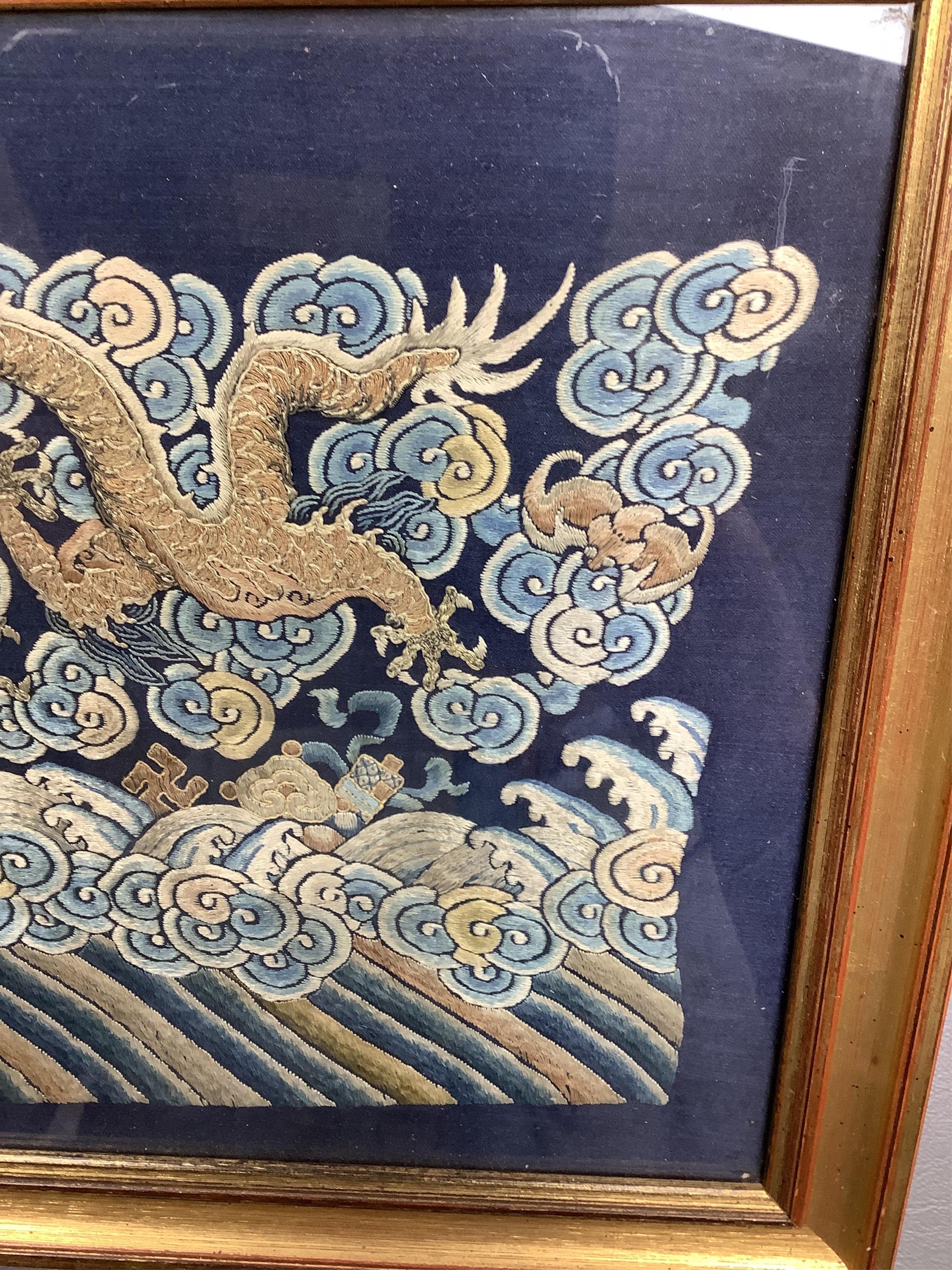 A framed late 19th / early 20th century Chinese silk embroidered five claw dragon panel from the base of a robe, 59cm wide x 23cm high. Condition - good, colours and embroidery strong